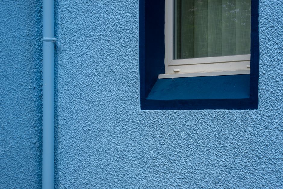 Blue painted wall with a window and a downpipe