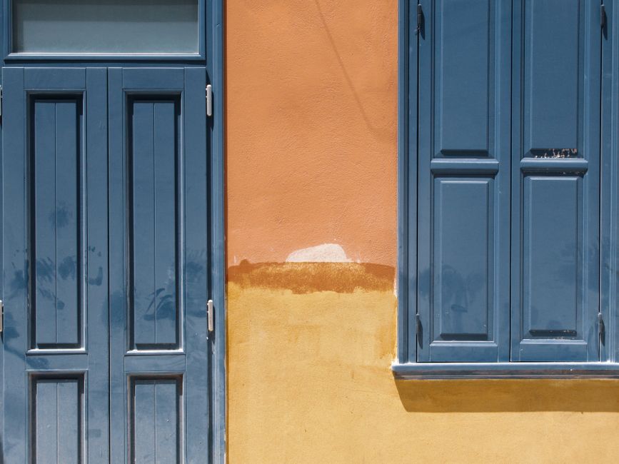 Orange painted wall with a blue door and window