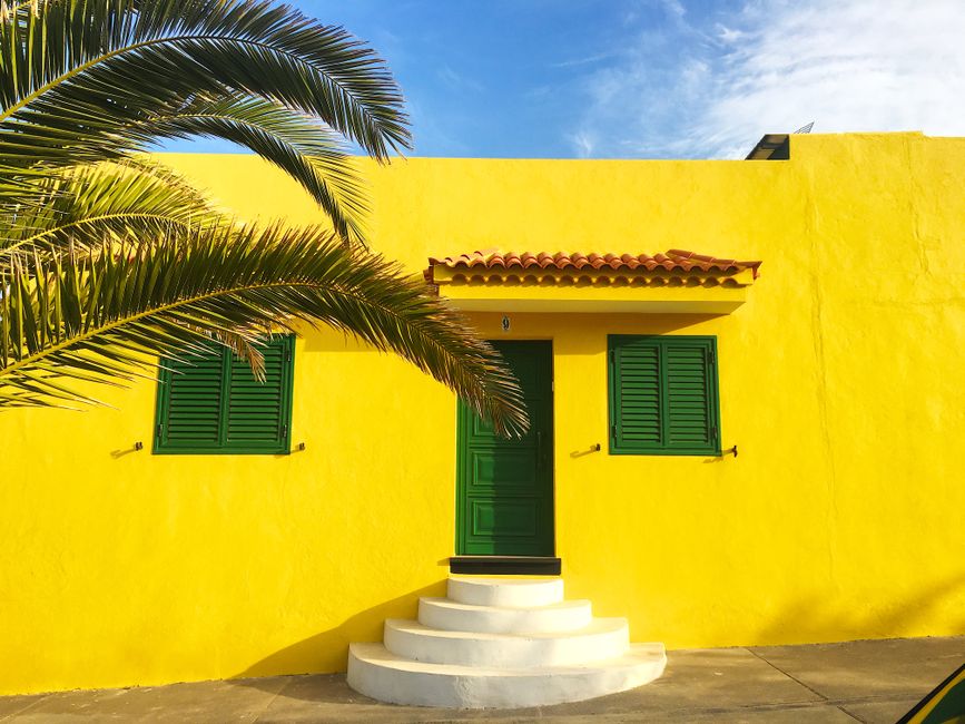 Yellow painted house front with green shutters