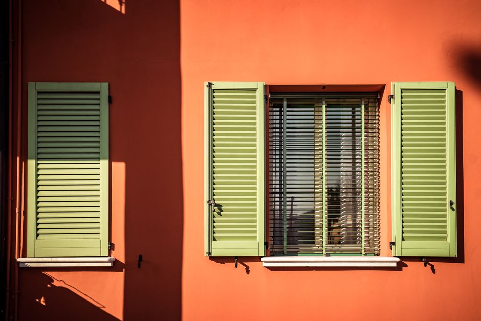 Orange painted wall with green shutters